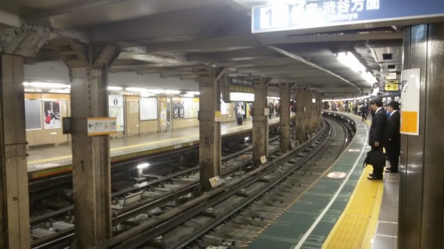 View of an empty train track and passengers waiting for the train to arrive.