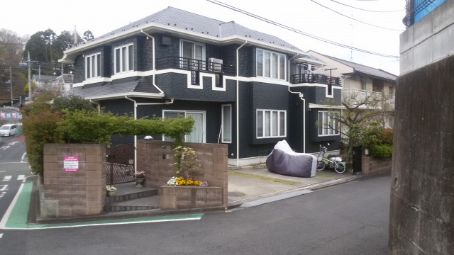 View of the front of a white and dark gray two-story Japanese home.