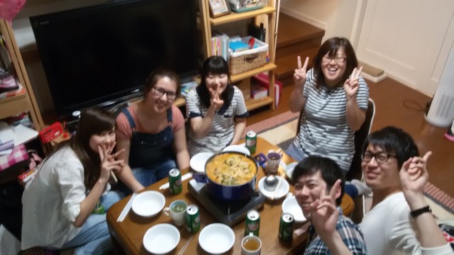 Student sitting around a small table with Japanese friends eating hotpot together.