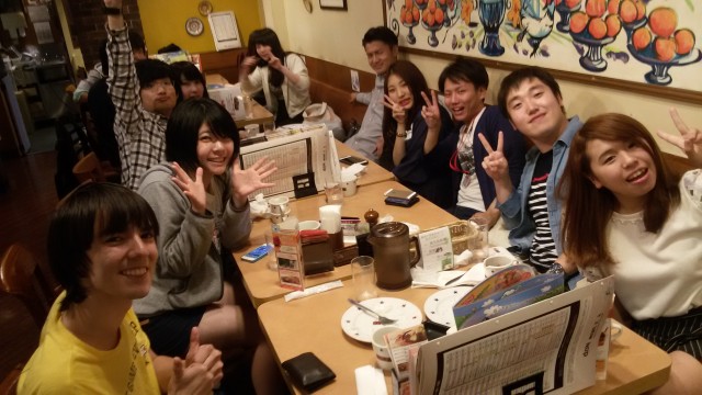 International and Japanese students posting for a photo at a restaurant dinner table.