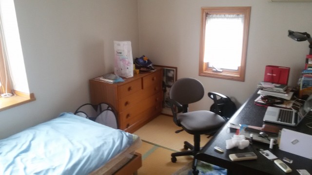 Student's homestay bedroom with a desk, dresser, and bed.